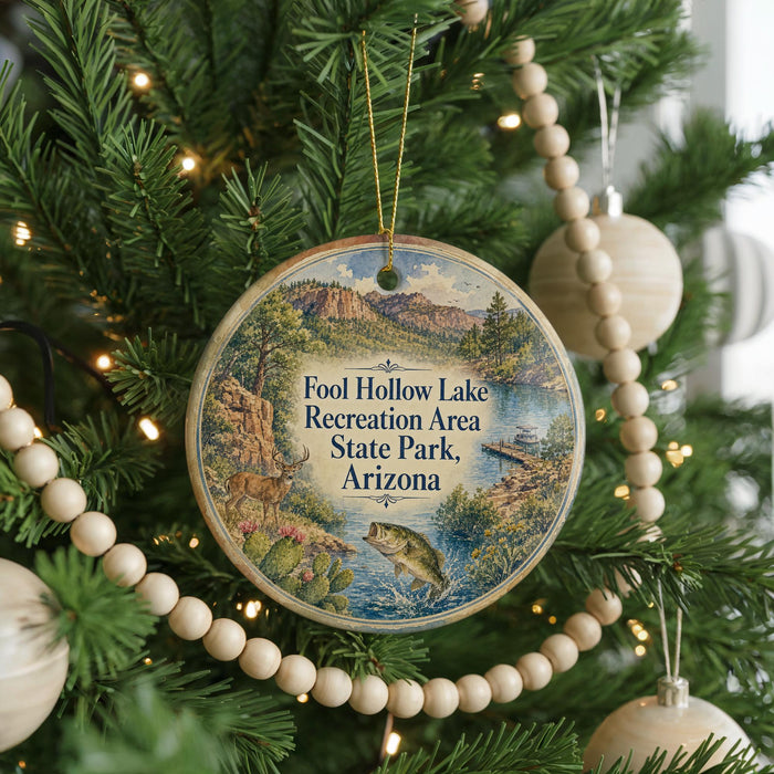 A circular ornament hanging on a Christmas tree, featuring a scenic landscape with mountains, a lake, and wildlife.