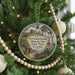 A round ornament hanging on a Christmas tree, featuring a scenic image of Fort King George Historic Site in Georgia.
