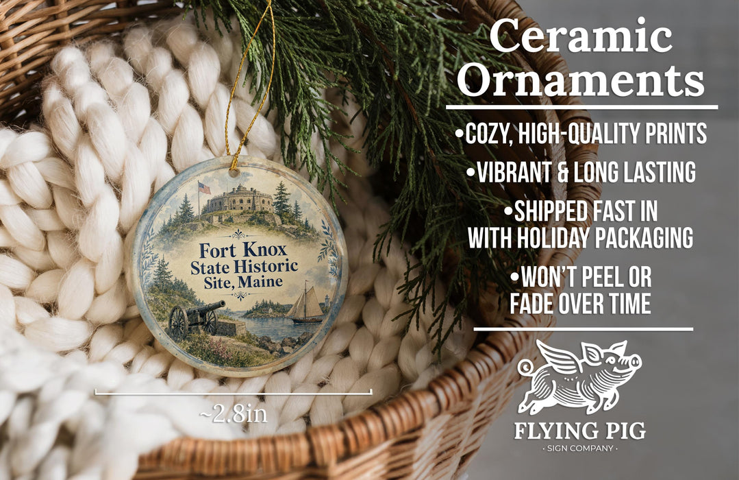 Ceramic ornaments, including a round ornament with a historical scene, are displayed in a basket with pine branches.