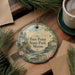 A decorative ornament with the text "Fort Point State Park, Maine" on it, surrounded by pine branches and a cup of coffee on a wooden surface.
