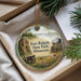 A round ornament with a painting of Fort Ridgely State Park in Minnesota, featuring a cannon, a building, and a field with flowers.