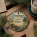 A round ornament with a painting of Fort Ross, a historic park in California, featuring a cannon, barrels, and a building.