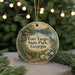 A round ornament with a painting of Fort Yargo State Park, Georgia, surrounded by pine branches and twinkling lights.