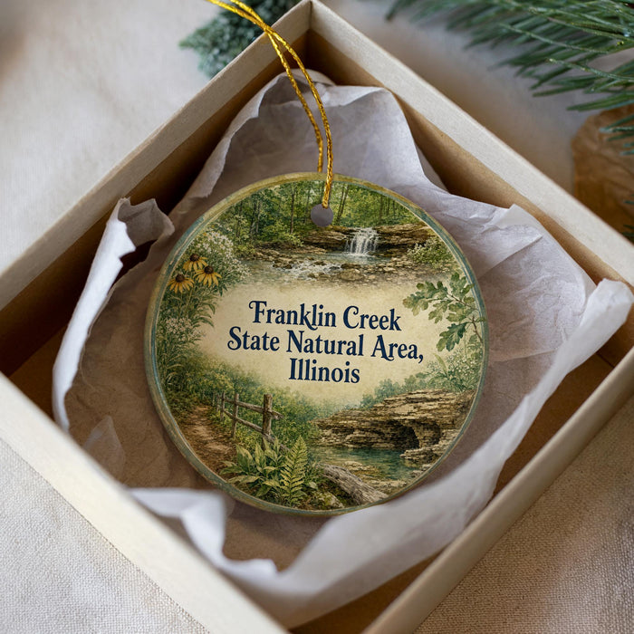 A round ornament with a scenic image of Franklin Creek, the State Natural Area in Illinois, displayed in a box with a gold string.