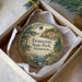 A decorative ornament in a box, featuring a scenic landscape with a lake, trees, and mountains, along with the text "Frontenac State Park, Minnesota".