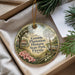 A decorative ornament with a scenic image of a house, palm trees, and flowers, hanging from a string.