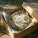 A decorative ornament in a wooden box, featuring a scenic image of a historic plantation in Florida.