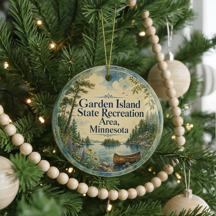 A round ornament hanging on a Christmas tree, featuring a scenic landscape with a lake and a canoe.