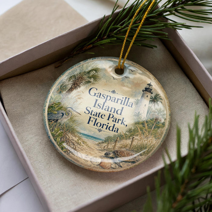 A decorative ornament in a box, featuring a scenic image of Casparilla Island, Florida, with a lighthouse and palm trees.