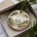 A decorative ornament in a box, featuring a scenic image of Casparilla Island, Florida, with a lighthouse and palm trees.