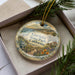 A decorative ornament with a scenic image of Gaviota State Park, California, displayed in a box with pine branches.