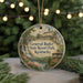 A round ornament with a painting of a resort park and a gazebo, surrounded by greenery and a string of lights.