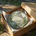 A decorative ornament in a wooden box, featuring a castle and trees, with the text "Gillette Castle State Park Connecticut" printed on it.