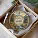 A decorative ornament in a box, featuring a scenic landscape with mountains, a cabin, and a stream.