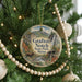 A round ornament hanging on a Christmas tree, featuring a scenic image of a waterfall and mountains.