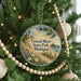 A round ornament hanging on a Christmas tree, featuring a scenic image of Grand Mere State Park, Michigan.