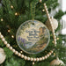 A circular ornament hanging on a Christmas tree, featuring a scenic image of the Great River Bluffs State Park in Minnesota.