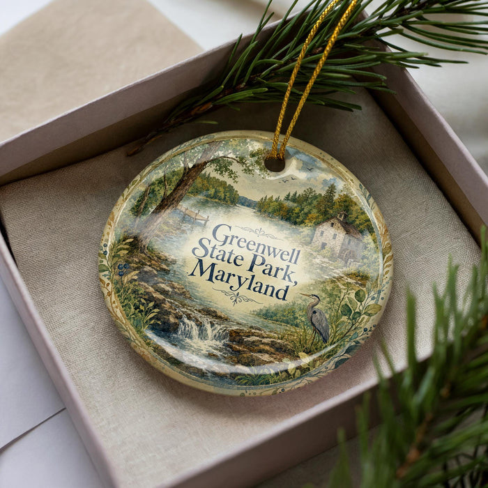 A decorative ornament in a box, featuring a scenic landscape with a waterfall and greenery, with the text "Greenwell State Park, Maryland" prominently displayed.
