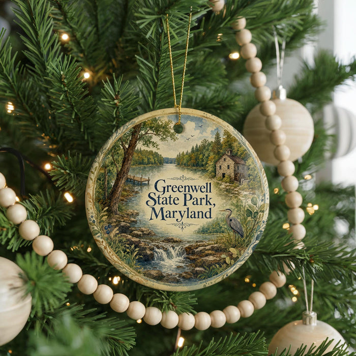 A round ornament hanging on a Christmas tree, featuring a scenic landscape with a river, trees, and a house.
