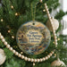 A round ornament hanging on a Christmas tree, featuring a scenic landscape with mountains, a waterfall, and palm trees.