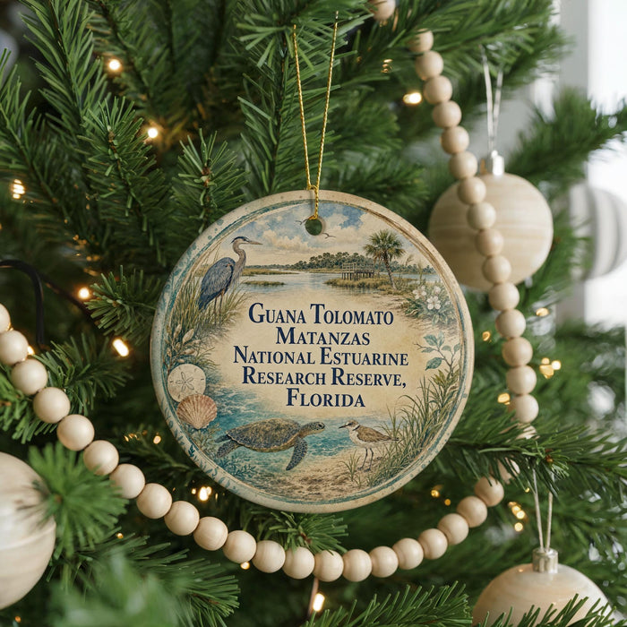 A round ornament hanging on a Christmas tree, featuring an illustration of a bird and a landscape with palm trees.