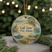 A round ornament with a beach scene and a bird, featuring the text "Gulf State Park, Alabama" on it, is displayed on a table with pine branches in the background.