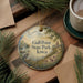 A round ornament with a scenic landscape of a lake, trees, and birds, along with the text "Gull Point State Park, Iowa".