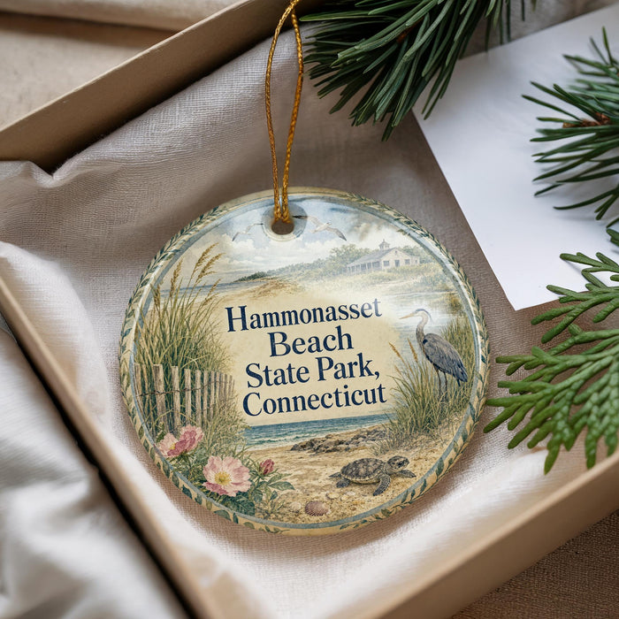 A decorative ornament with a beach scene and a bird, placed in a box with pine branches.