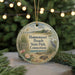A round ornament with a beach scene and a bird, hanging on a string.