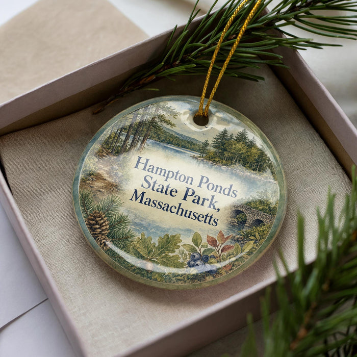 A decorative ornament in a box, featuring a scenic image of a pond surrounded by trees and mountains, with the text "Hampton Ponds State Park, Massachusetts" printed on it.