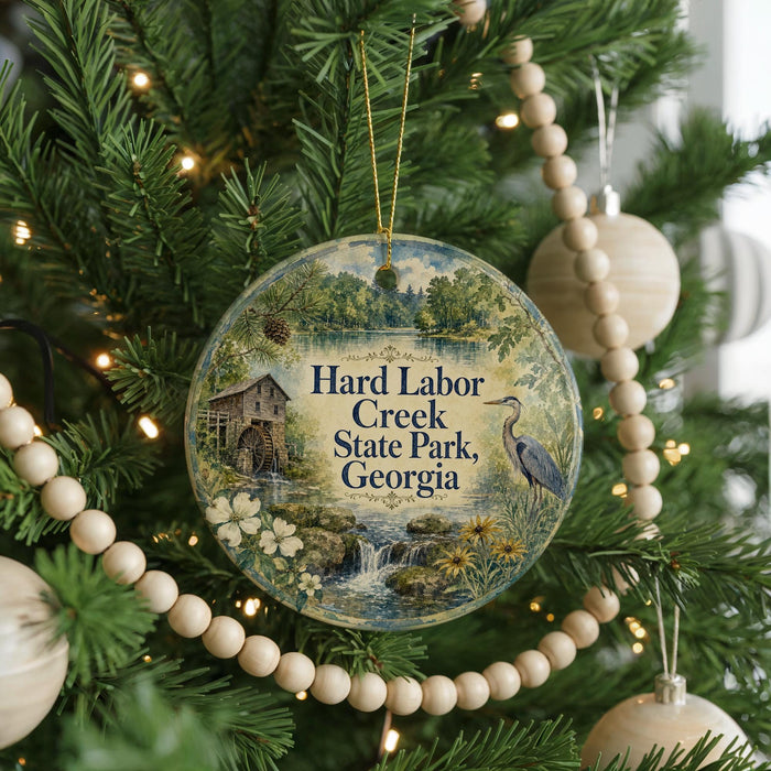 A round ornament hanging on a Christmas tree, featuring a scenic image of Hard Labor Creek State Park, Georgia.