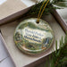 A round ornament with a scenic image of the state park of Massachusetts, featuring a forest, a waterfall, and a bridge.