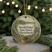 A round ornament with a scenic image of a forest and a waterfall, hanging from a string.