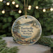 A decorative ornament featuring a scenic landscape with a lighthouse, trees, and a body of water, hanging on a string.