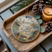 A decorative ornament featuring a scenic image of San Simeon State Park, California, with a candle and pine cones on a wooden tray.