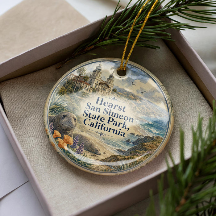 A decorative ornament in a box, featuring a scenic image of a coastal landscape with a building and palm trees.