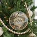 A round ornament hanging on a Christmas tree, featuring a scenic image of a coastal town with palm trees and a beach.