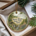 A decorative ornament with a scenic landscape of Heery Woods State Park, Iowa, featuring a river, trees, and a bridge.