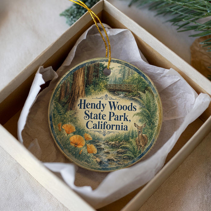 A round ornament with a picture of a forest and a deer, placed in a box with tissue paper.