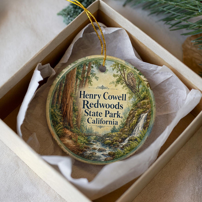 A round ornament with a painting of a forest scene, featuring a waterfall and trees, is displayed in a box.