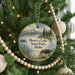 A round ornament hanging on a Christmas tree, featuring a moose and a scenic landscape with mountains in the background.