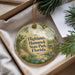 A decorative ornament with a scenic image of a tropical forest, featuring palm trees, a bird, and a body of water, hanging from a string.