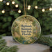 A round ornament with a scenic illustration of a forest and a bird, hanging from a string.
