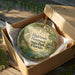 A decorative ornament in a brown box, featuring a lush, tropical scene with palm trees and other greenery, along with the text "Highlands Hammock State Park, Florida".