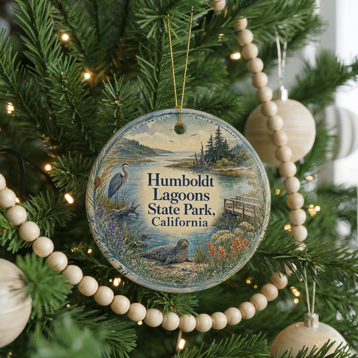 A round ornament hanging on a Christmas tree, featuring a scenic image of a lake surrounded by trees and wildlife.