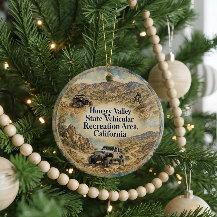 A Christmas ornament hanging on a tree, featuring a desert landscape with jeeps and mountains in the background.