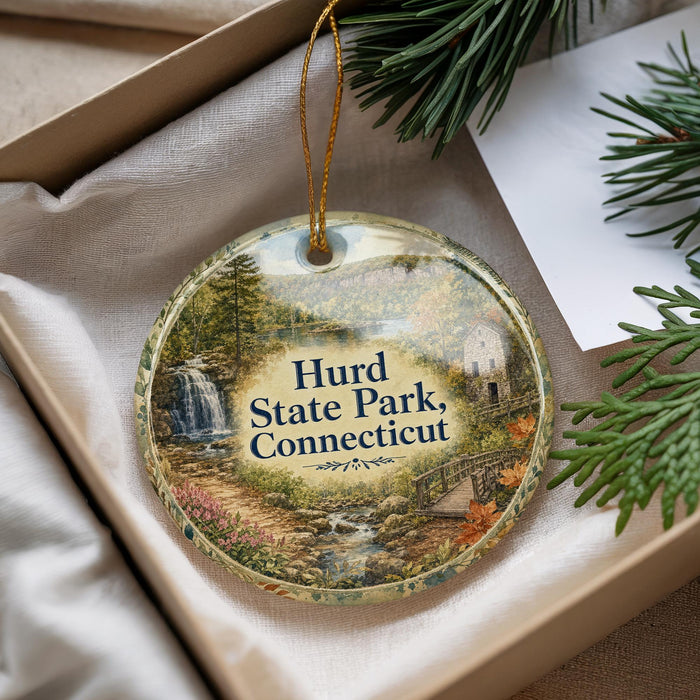A decorative ornament with a scenic landscape of Hurd State Park, Connecticut, featuring a waterfall, a bridge, and pine trees.