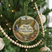 A round ornament hanging on a Christmas tree, featuring a scenic landscape with a waterfall and a bridge.