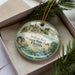 A decorative ornament in a box, featuring illustrations of a historic site and tropical elements, with the text "Indian Key Historic State Park, Florida" prominently displayed.