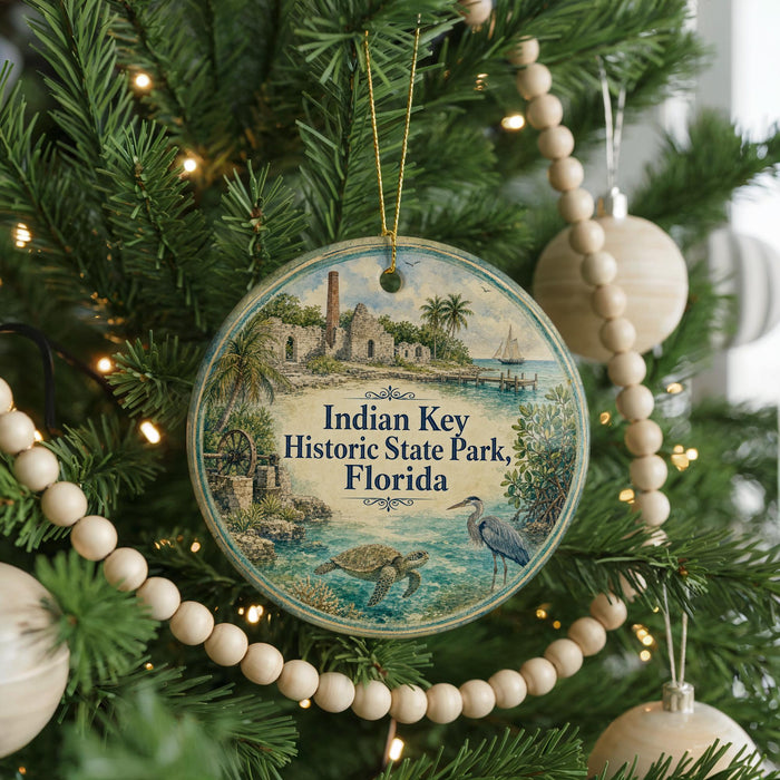 A round ornament hanging on a Christmas tree, featuring an illustration of a tropical beach scene with palm trees, a lighthouse, and a bird.
